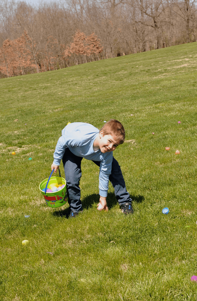 Boy in a field doing egg hunt
